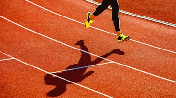Esportista correndo em pista de atletismo - Getty Images