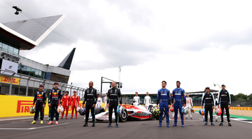 Pilotos da Fórmula 1 posicionados na pista em frente ao carro de corrida - GettyImages