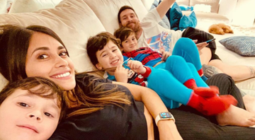 Messi, Antonela Roccuzzo e os filhos do casal juntos no sofá sorrindo para a câmera - Reprodução/Instagram