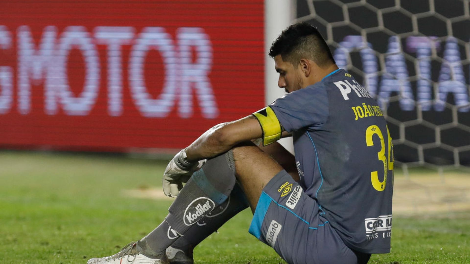 João Paulo sentado no gramado com a camisa do Santos