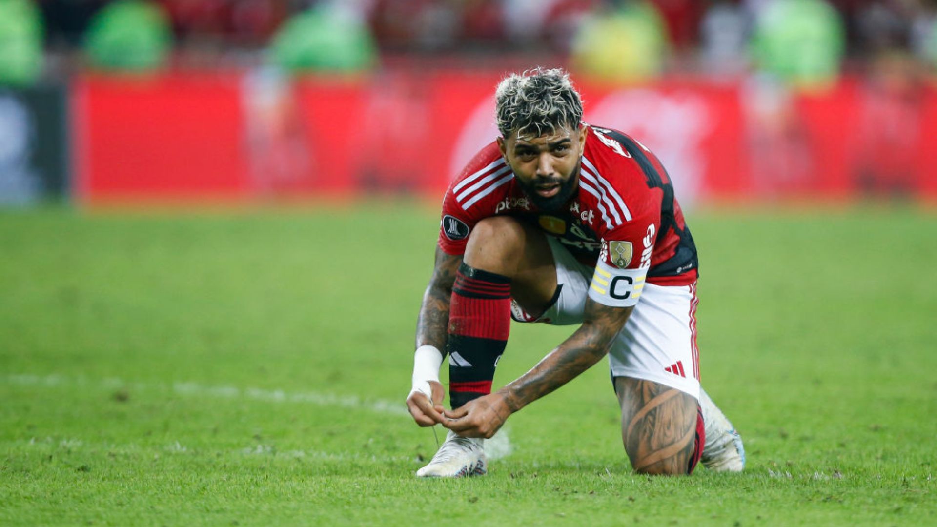 Gabigol amarrando a chuteira em jogo do Flamengo