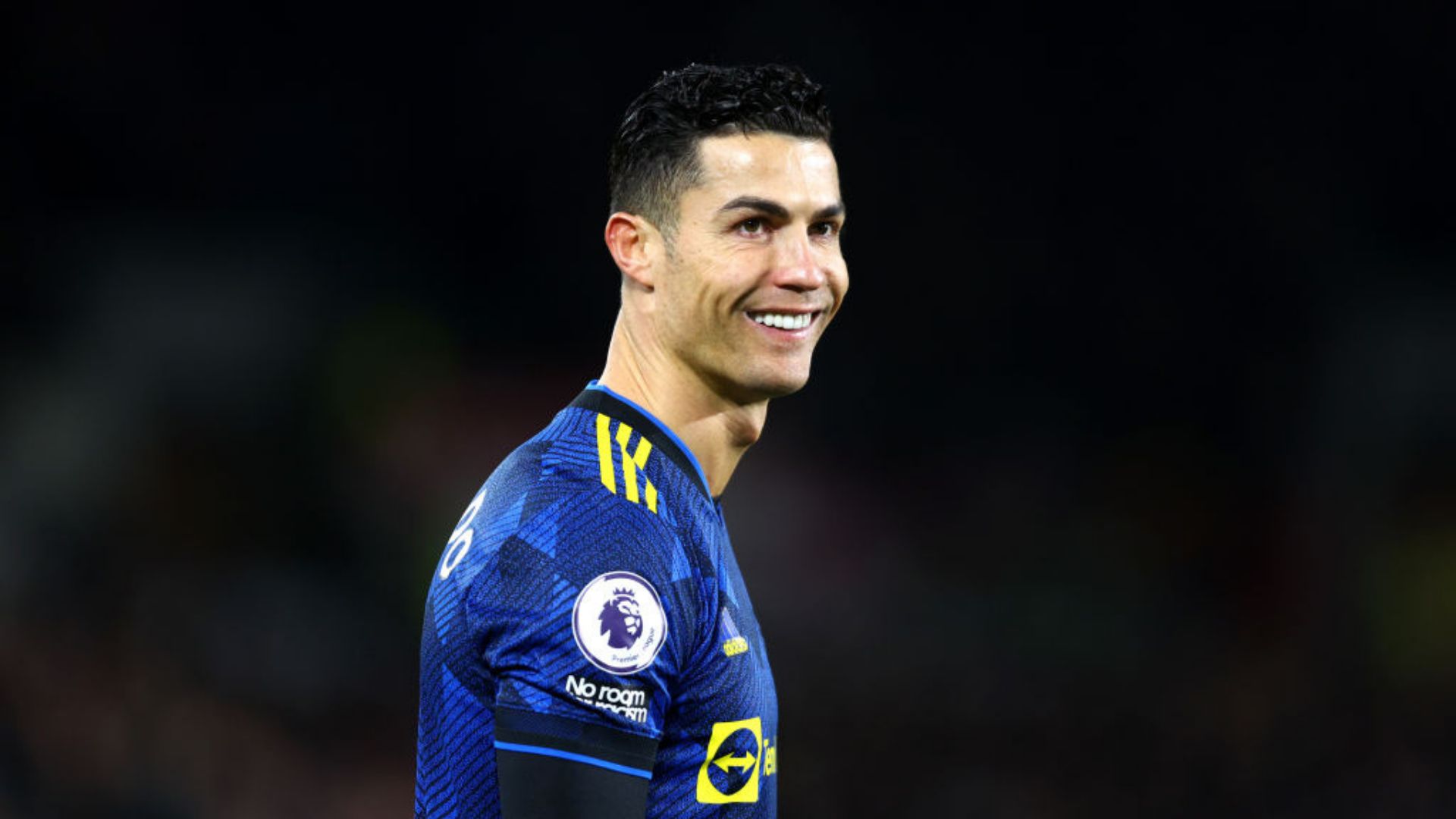 Cristiano Ronaldo sorrindo em campo com a camisa do United
