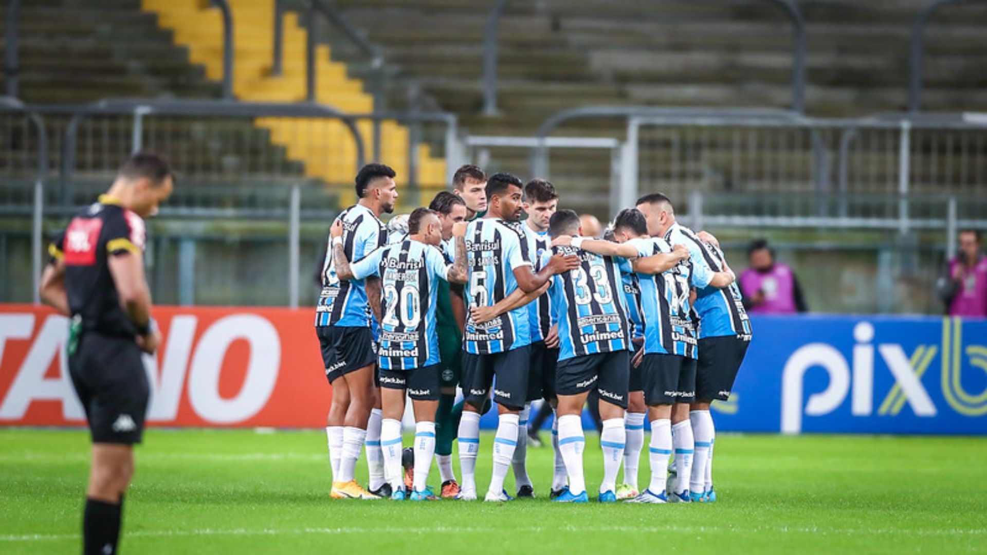 Jogadores do Grêmio reunidos dentro de campo antes da partida